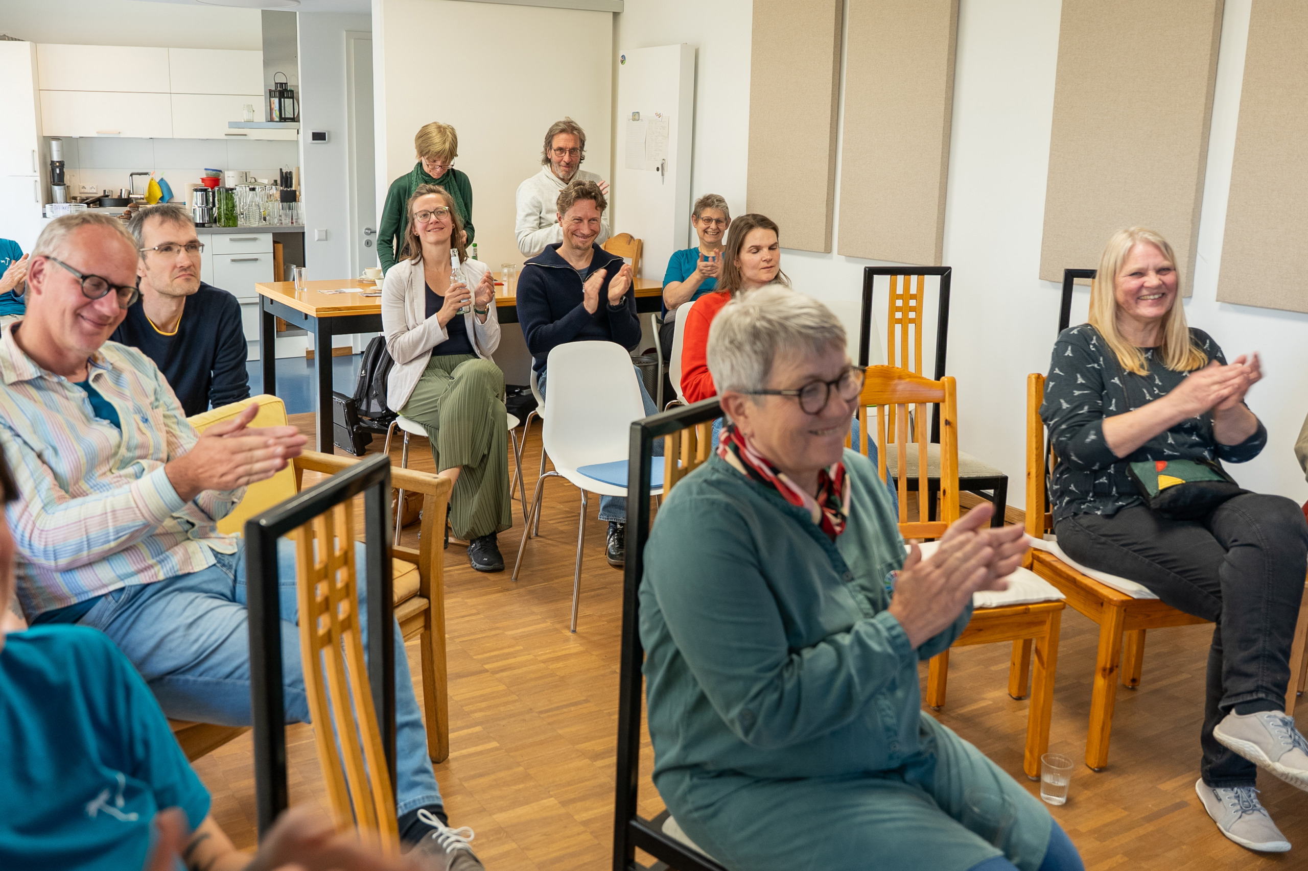 Ein Publikum mit vielen lächelnden Gesichtern applaudiert.